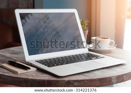 Laptop with tablet, pen and a cup of fresh coffee latte art on wooden table in coffee shop
