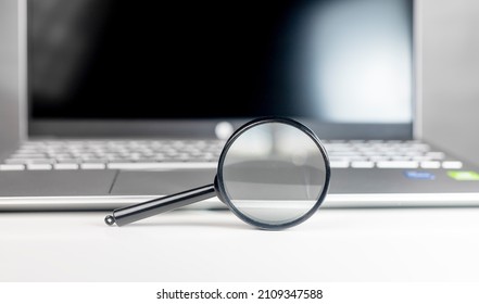 Laptop through magnifying lens. Internet search and SEO research concept.