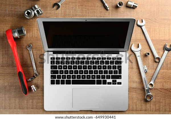 Laptop and tools\
for car repair on wooden\
table