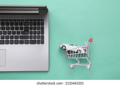 Laptop With A Toy Car In A Shopping Trolley On A Blue Background. Online Car Purchase. Top View