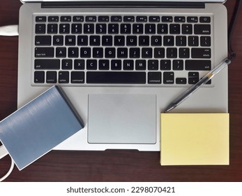 Laptop transferring data in external hard drive storage with yellow paper note, paper clips, pen and binder clips background at office work place. Selective focus