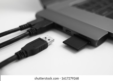 Laptop with USB Type-C adapter with pluged USB cables and SD card. The USB adapter under the Type-C connector for laptop. Multiport station for laptop with multiple different ports. Hub Converter.