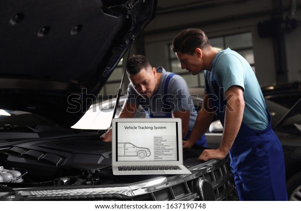 Laptop with vehicle tracking system and\
blurred mechanics on background. Auto\
diagnostic