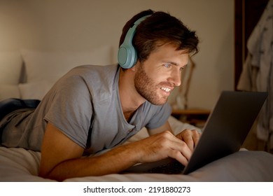 Laptop, video and man streaming a movie in his bedroom on tv via internet while relaxed, smile and enjoying content. Headphones, house and happy male watching series on computer pc at night at home - Powered by Shutterstock