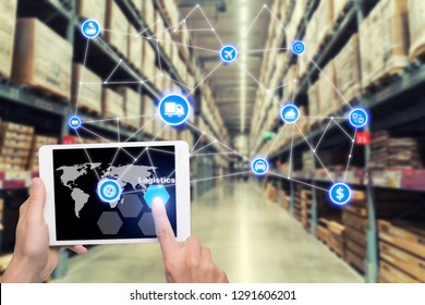 Laptop With White Blank Screen With Global Map On Brown Wooden Desk And Blurred Warehouse Store Background. Use For Cargo Import, Export, Logistics Background
