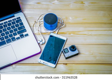 Laptop,mobile Phone,action Cam,Speakers, Headphones On Wood Background