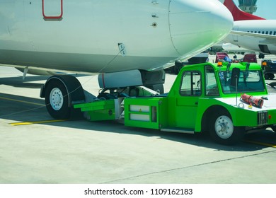 Large aircraft being pulled by airport tug tractor taxing on airfield into docking position for passenger boarding the airplane
