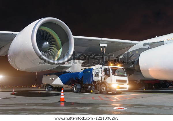 Large aircraft jet\
engines, Fueling a huge airplane, a truck with fuel with hoses\
connected to a fuel tank