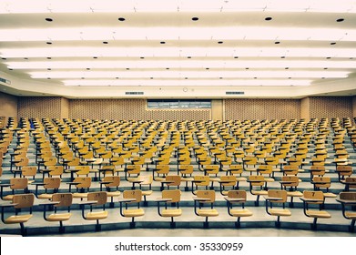 A large amount of empty seats with tables in a lecture hall