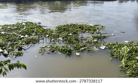 Large amounts of garbage accumulate in a river stream, highlighting environmental pollution and waste management problems in urban waterways.