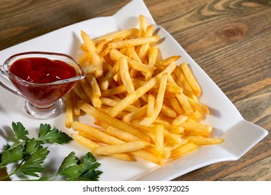 Large Amounts Of Golden Fries On A Curly Square Plate With Ketchup And Parsley On The Table Top