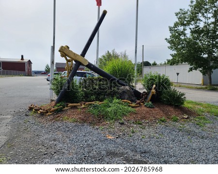 A large anchor sitting in a tiny gardened area in the middle of an intersection. This ornament is symbolic of the nautical community where it lays in Nova Scotia.