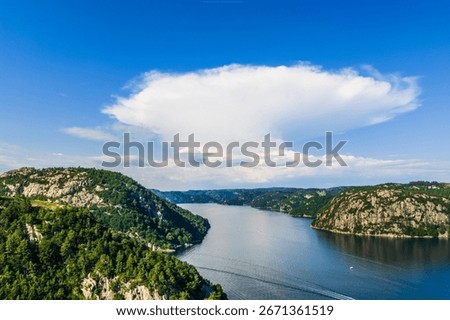 Large anvil shaped cloud over scenic fjord landscape