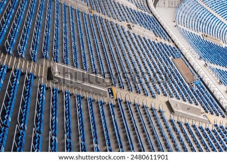 Large arena with rows of empty blue stadium seats, showcasing venue expansive and orderly seating arrangement. Empty blue seats in a large stadium. Architectural and sports venue concept. 