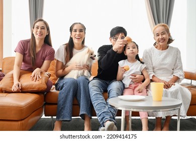 A Large Asian Family Consists Of Grandmothers, Fathers, Mothers, Older Sisters And Cute Girls. They Are Spending Time Together Happily In The Living Room, Playing Games, Watching TV, Eating Snacks. Ha