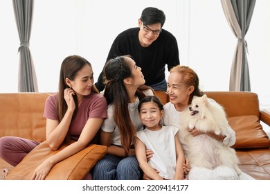 A Large Asian Family Consists Of Grandmothers, Fathers, Mothers, Older Sisters And Cute Girls. They Are Spending Time Together Happily In The Living Room, Playing Games, Watching TV, Eating Snacks. Ha