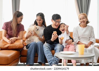 A Large Asian Family Consists Of Grandmothers, Fathers, Mothers, Older Sisters And Cute Girls. They Are Spending Time Together Happily In The Living Room, Playing Games, Watching TV, Eating Snacks. Ha