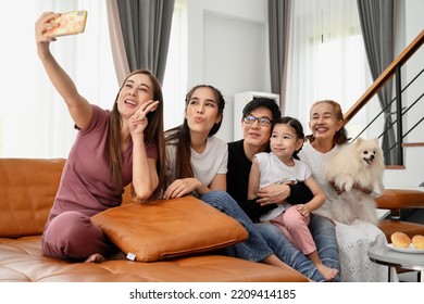 A Large Asian Family Consists Of Grandmothers, Fathers, Mothers, Older Sisters And Cute Girls. They Are Spending Time Together Happily In The Living Room, Playing Games, Watching TV, Eating Snacks. Ha