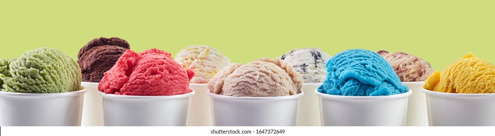 Large assortment of summer ice cream desserts in different flavors served in takeaway tubs over yellow in a wide panorama banner or header