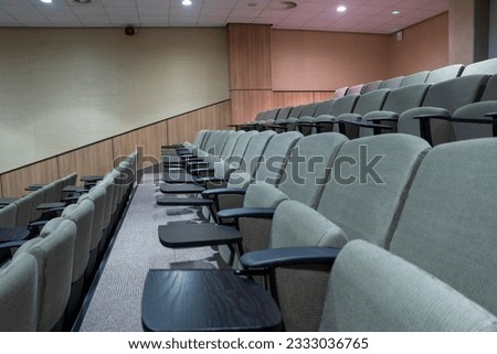 large auditorium rows of empty chairs with small side tables  in a conference center