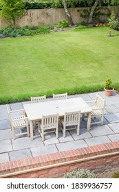 Large Back Garden In UK In Summer, With Wooden Furniture On A Garden Patio Terrace