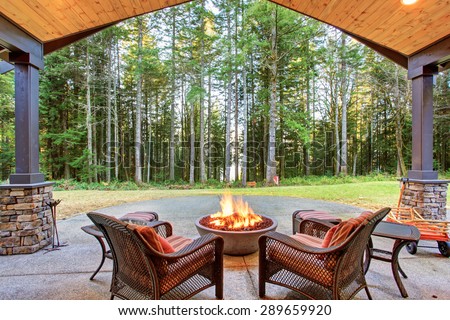 Large back yard with grass and covered patio with fire pit.