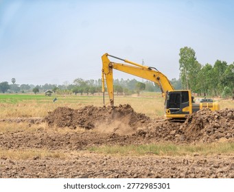 Large backhoe loader performing groundwork and soil excavation in an open field under a clear blue sky.