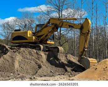 A large backhoe loader standing on a pile of earth.