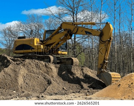 A large backhoe loader standing on a pile of earth.