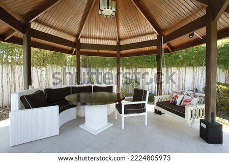 Large backyard gazebo with table and cushioned and hanging chairs
