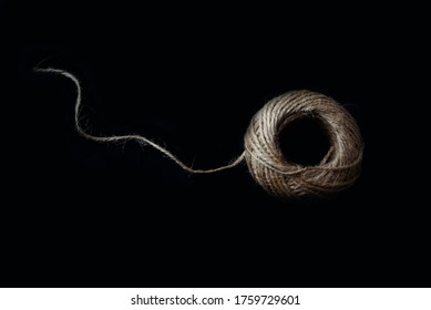 A Large Ball Of Light Twine With The Loose End On A Black Background