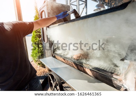Large barbecue smoker grill at the park. Meat prepared in barbecue smoker.