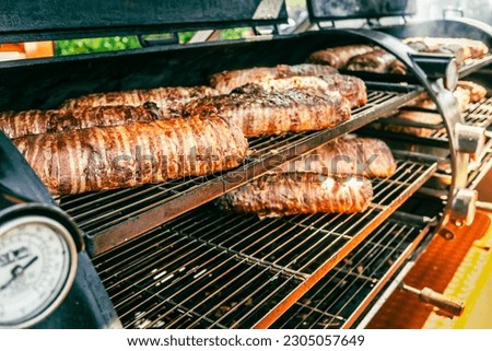 Large barbecue smoker grill at the park. Meat and bacon prepared in barbecue smoker.