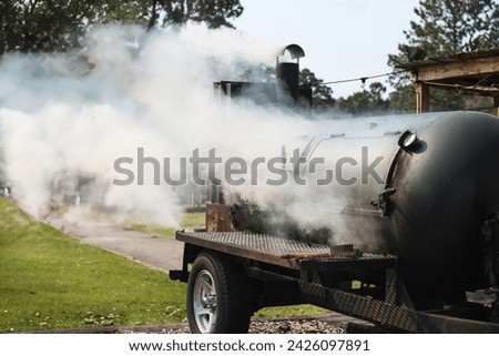 Large barbecue smoker grill at the park. Unleashing Flavors Amidst the Greens with a Hearty BBQ Session. A Smoky Affair with a Barbecue Grill. Slow cooking.