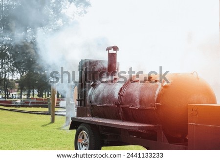 Large barbecue smoker grill at the park. Unleashing Flavors Amidst the Greens with a Hearty BBQ Session. A Smoky Affair with a Barbecue Grill. Slow cooking.