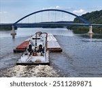 Large barge traveling under the Dale Gardner Veterans Memorial Bridge at Savanna illinois on the Mississippi River