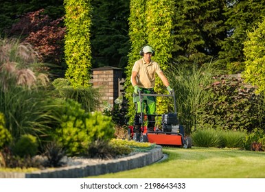 Large and Beautiful Landscape Garden in the Backyard of Residential House. Professional Landscaper in Protective Headphones Taking Care of Design Appearance by Mowing the Lawn. - Shutterstock ID 2198643433