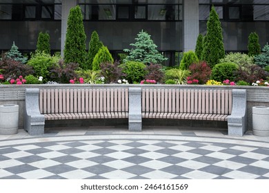 Large beautiful wooden bench with stone railings. Against a background of flowers and green ornamental shrubs. - Powered by Shutterstock