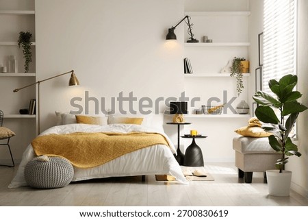 Large bed with linens, bedside tables, poufs and shelving units in bedroom