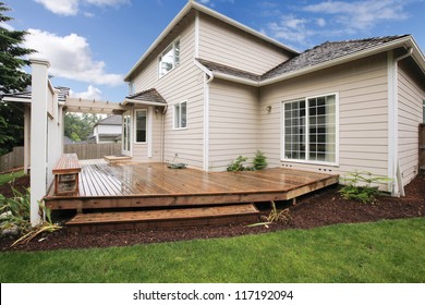 Large Beige House With Porch From The Backyard With Grass And Mulch.