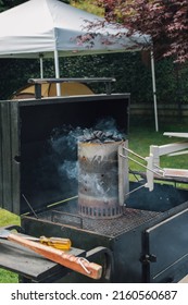 Large Black Barbecue With Smoking Charcoal Chimney At Outdoor Backyard Cookout