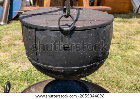 A large black metal cooking pot replica used by medieval vikings displayed by a re-enactment troupe at a village fair