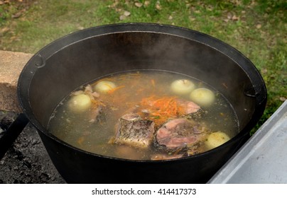 A Large Black Vat With Fish Soup Outdoors