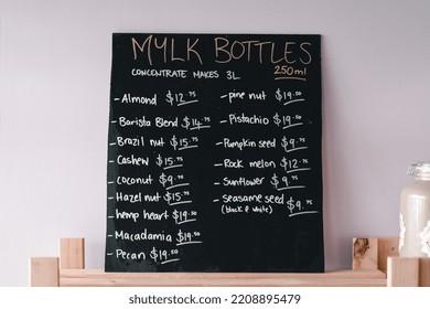 Large Blackboard On The Nice Wooden Shelf Leaning Against The Wall With The Prices Of The Different Types Of Milk Written By Hand With A Chalk In A Nice Coffee Shop, The Mylk Bar, New Zealand