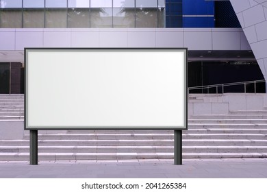 Large Blank Advertising Poster Billboard Banner Mockup In Front Of Building In Urban City; Digital Lightbox Display Screen For OOH Media. Speckled Textured Concrete Cement Staircase In Background.