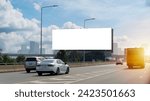 A large, blank billboard on the side of a highway. The billboard is white. It is located in a rural area, with trees and grass in the background. The sun is shining and the sky is blue, clipping path.