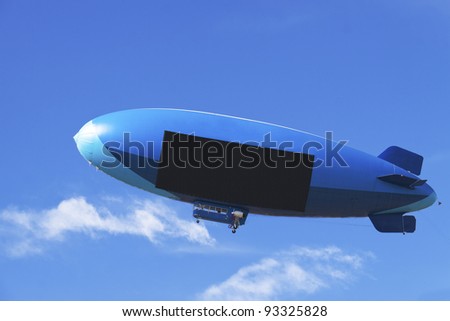 Large blimp with black digital screen on a blue background with white clouds