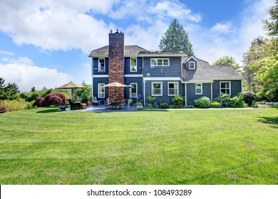 Large Blue House Exterior With Grass And Chimney.