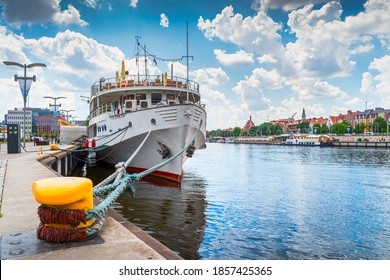 Large boat docked or moored on Customs Quay, view on promenade and boulevards on Odra River embarkment with old town in background in Szczecin, Poland