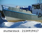 Large boats docked in snow on shore of frozen Great Slave Lake